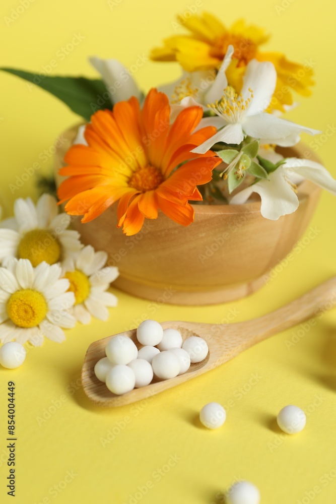 Homeopathic remedy and flowers on yellow background Homeopathic remedy and flowers on yellow background