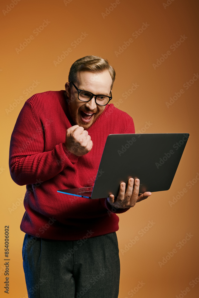 A stylish man in a red sweater actively using a laptop. A stylish man in a red sweater actively using a laptop.
