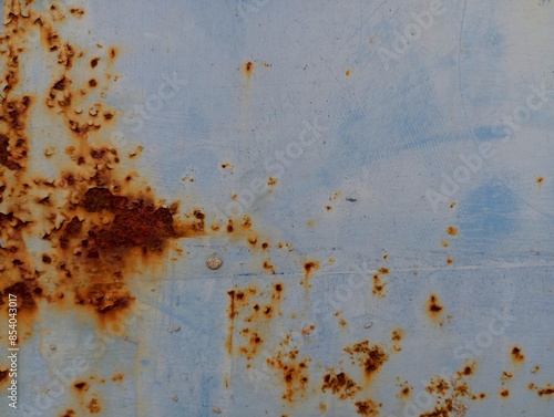 Rust spots on the metal surface. Texture of old metal painted in light blue color with traces of old rust. photo