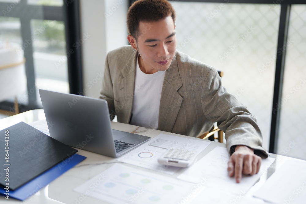 Attractive confident millennial Asian Business man using laptop computer and professional working investor start up project business planning in office. Attractive confident millennial Asian Business man using laptop computer and professional working investor start up project business planning in office.