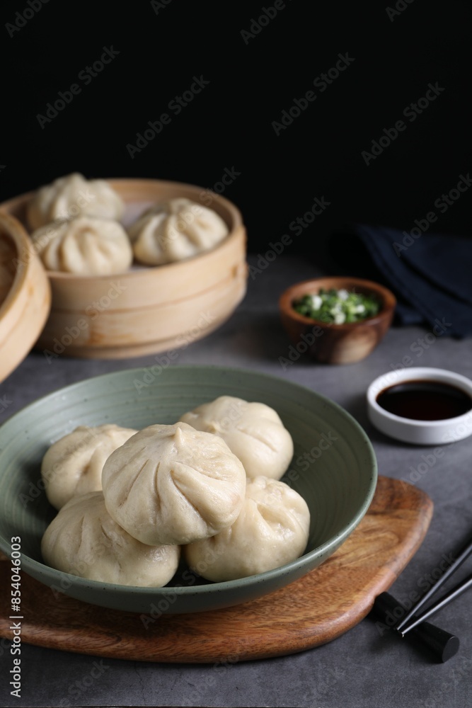 Fototapeta premium Delicious bao buns (baozi) in bowl on grey table, closeup