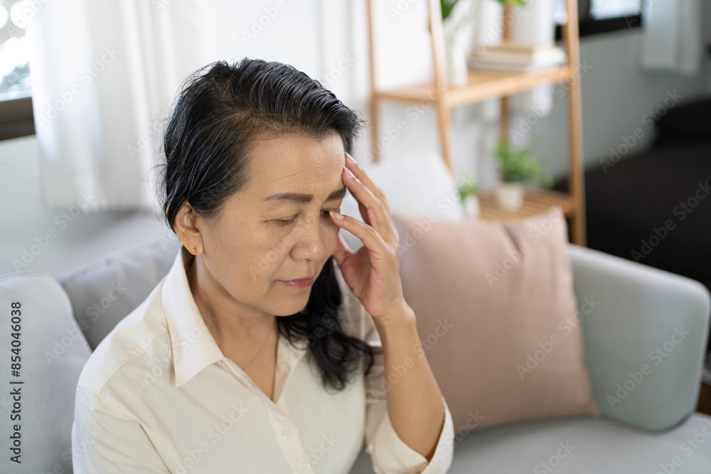 Middle age Asian woman touching forehead having headache suffering from. migraine feeling sick or depression Middle age Asian woman touching forehead having headache suffering from. migraine feeling sick or depression