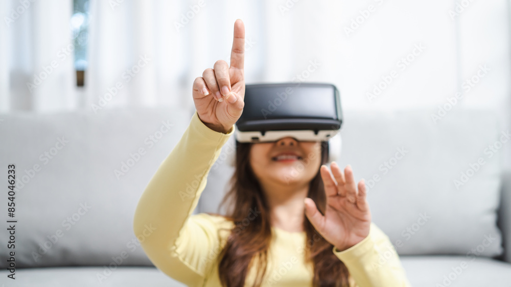 Young Asian woman wearing virtual reality touching air during the VR experience Future technology concept. Young Asian woman wearing virtual reality touching air during the VR experience Future technology concept.