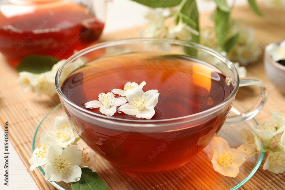Hot jasmine tea in cup and flowers on white wooden table, closeup Hot jasmine tea in cup and flowers on white wooden table, closeup