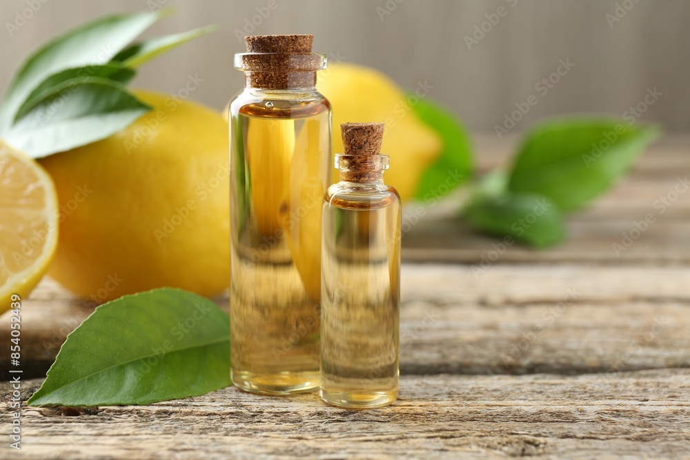 Essential oils in bottles, lemons and green leaves on wooden table, closeup. Space for text Essential oils in bottles, lemons and green leaves on wooden table, closeup. Space for text