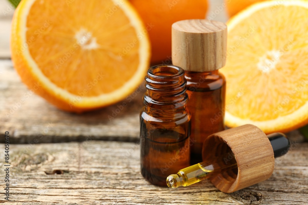 Essential oils in bottles, dropper and oranges on wooden table, closeup Essential oils in bottles, dropper and oranges on wooden table, closeup