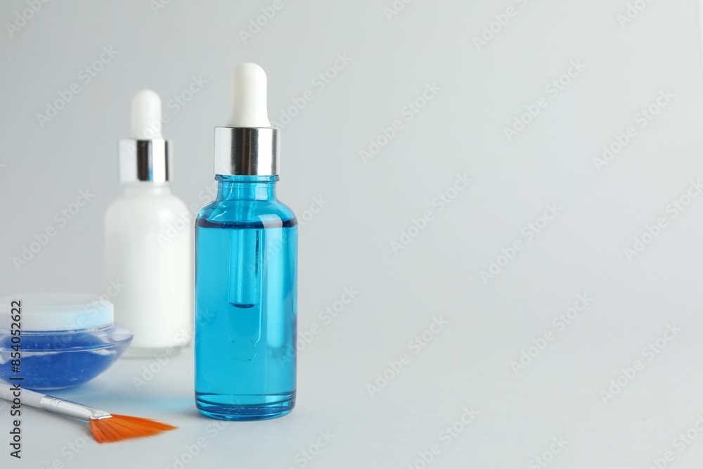 Bottles of chemical peel, jar and brush on light background, space for text. Peeling procedure Bottles of chemical peel, jar and brush on light background, space for text. Peeling procedure