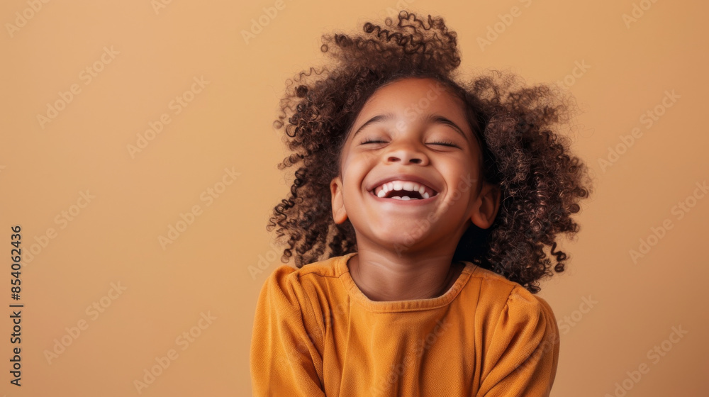 an African American girl showing joy on a beige studio background an African American girl showing joy on a beige studio background
