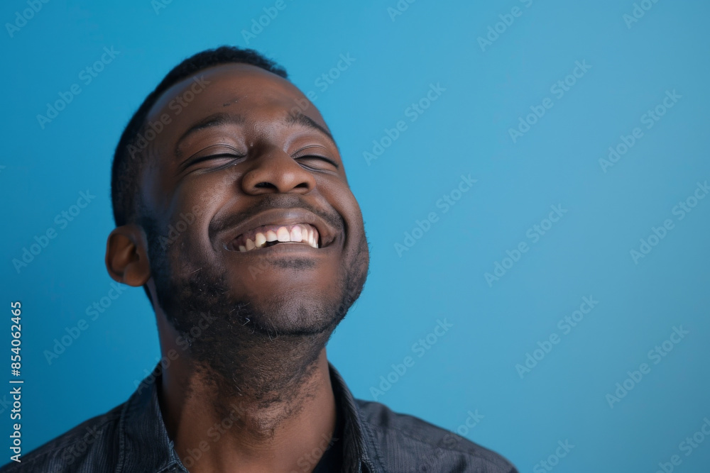 an African American man expressing contentment on a blue studio background an African American man expressing contentment on a blue studio background