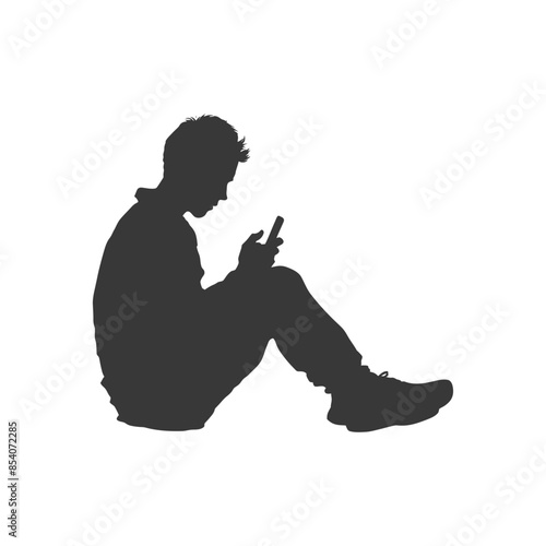 Silhouette of seated young man absorbed in mobile phone.