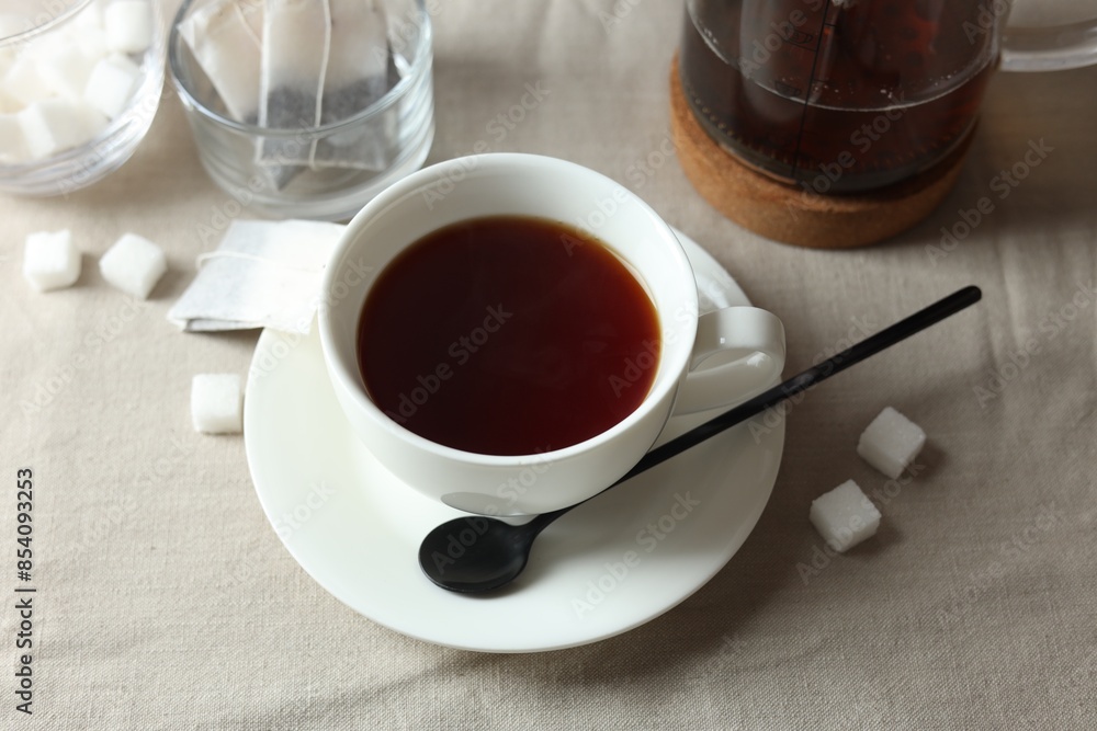 Tasty tea in cup and sugar cubes on light table Tasty tea in cup and sugar cubes on light table