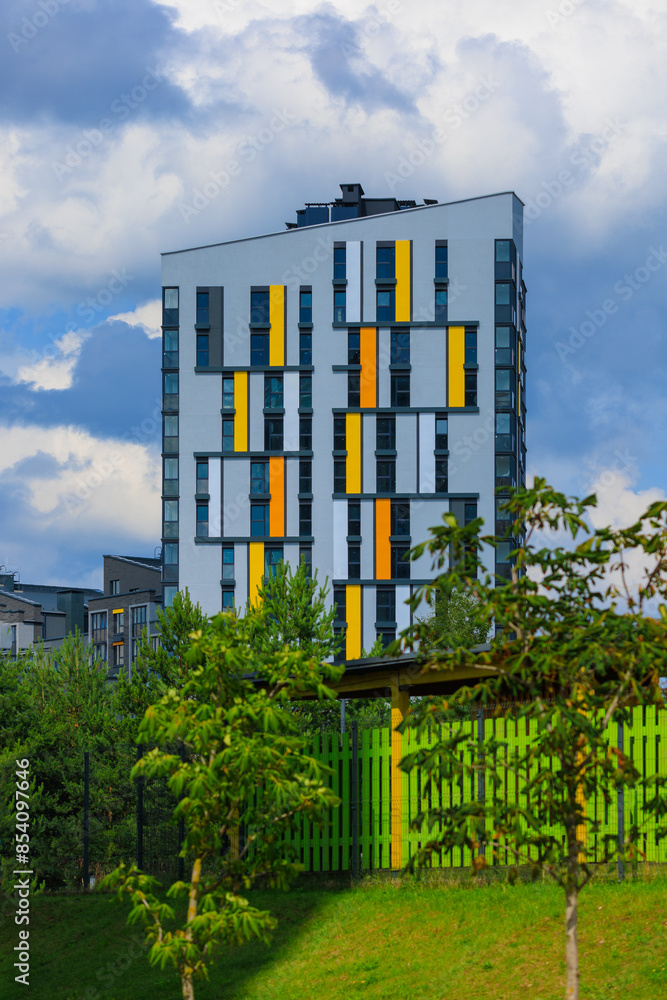 Fototapeta premium City view on a sunny day. Modern building and houses against the blue sky.