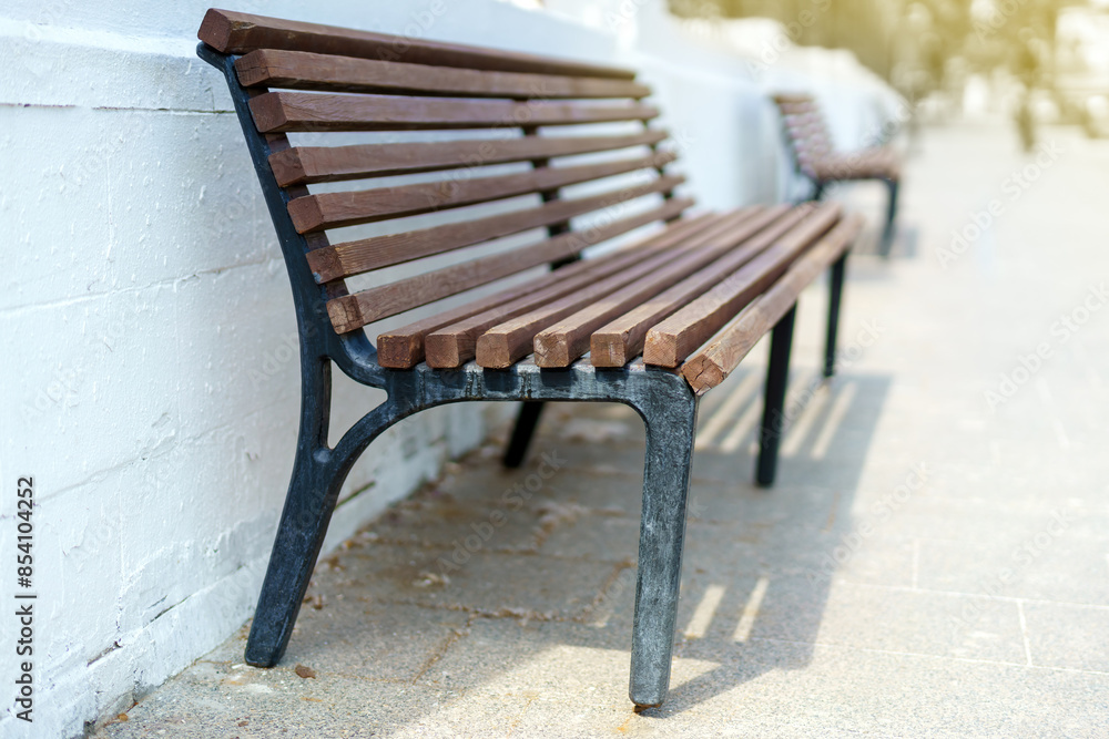 A line of benches aligned by a whitewashed brick wall, offering a tranquil urban resting spot A line of benches aligned by a whitewashed brick wall, offering a tranquil urban resting spot