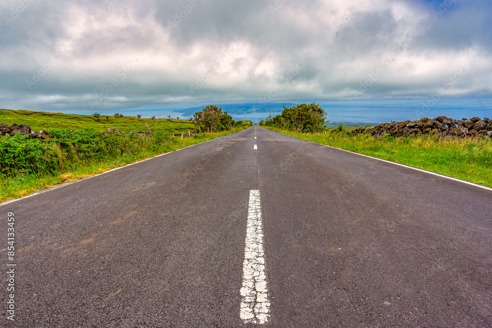 Tarmac road with the beautiful landscape surrounding the island of Pico in the Azores archipelago. Tarmac road with the beautiful landscape surrounding the island of Pico in the Azores archipelago.