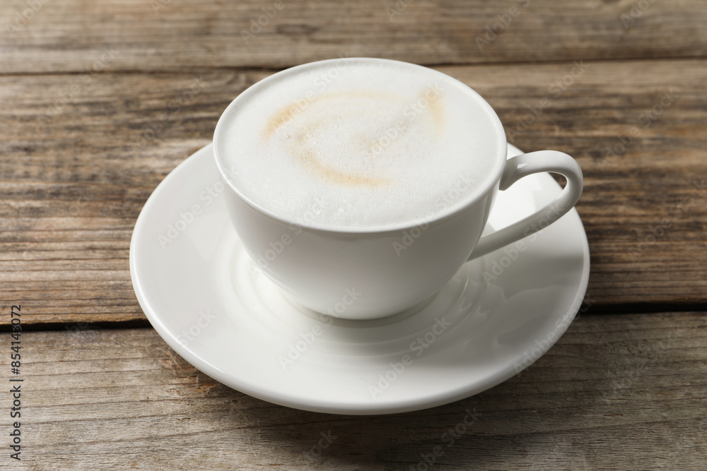 Tasty cappuccino in coffee cup on wooden table, closeup Tasty cappuccino in coffee cup on wooden table, closeup