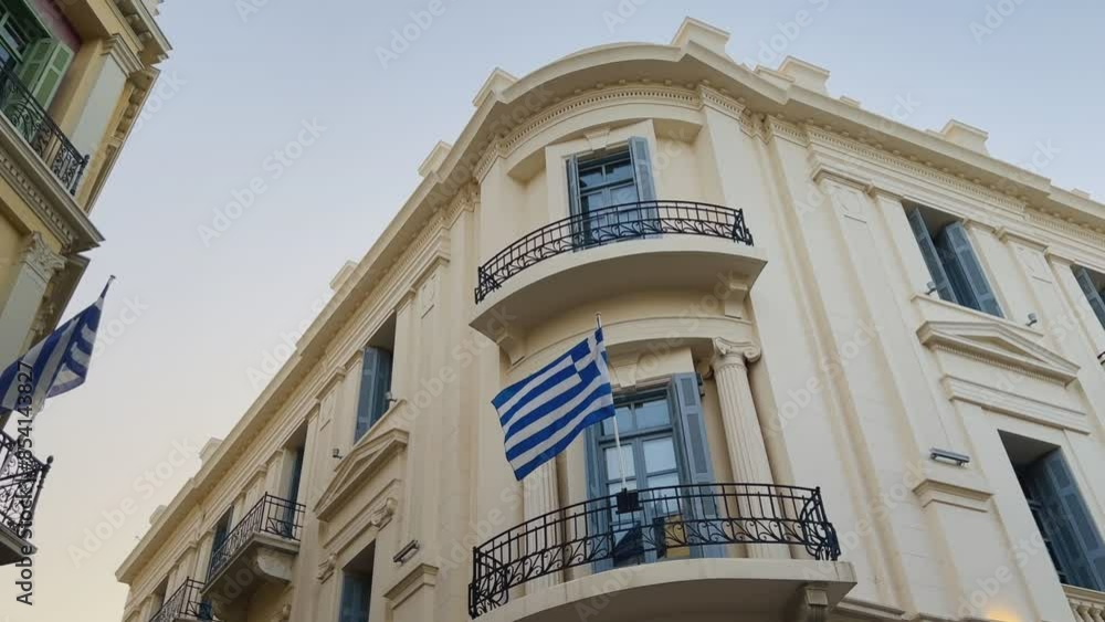 The facade of a historical building with a Greek flag on a balcony The facade of a historical building with a Greek flag on a balcony