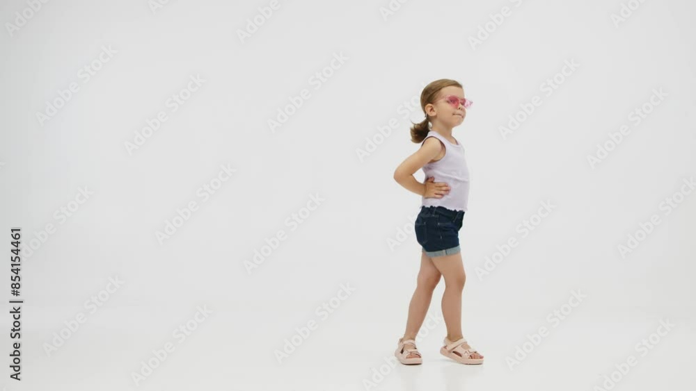 Fashionable, stylish little girl dancing, having fun and posing on a white studio background. Fashion, children's clothing and entertainment concept. Fashionable, stylish little girl dancing, having fun and posing on a white studio background. Fashion, children's clothing and entertainment concept.