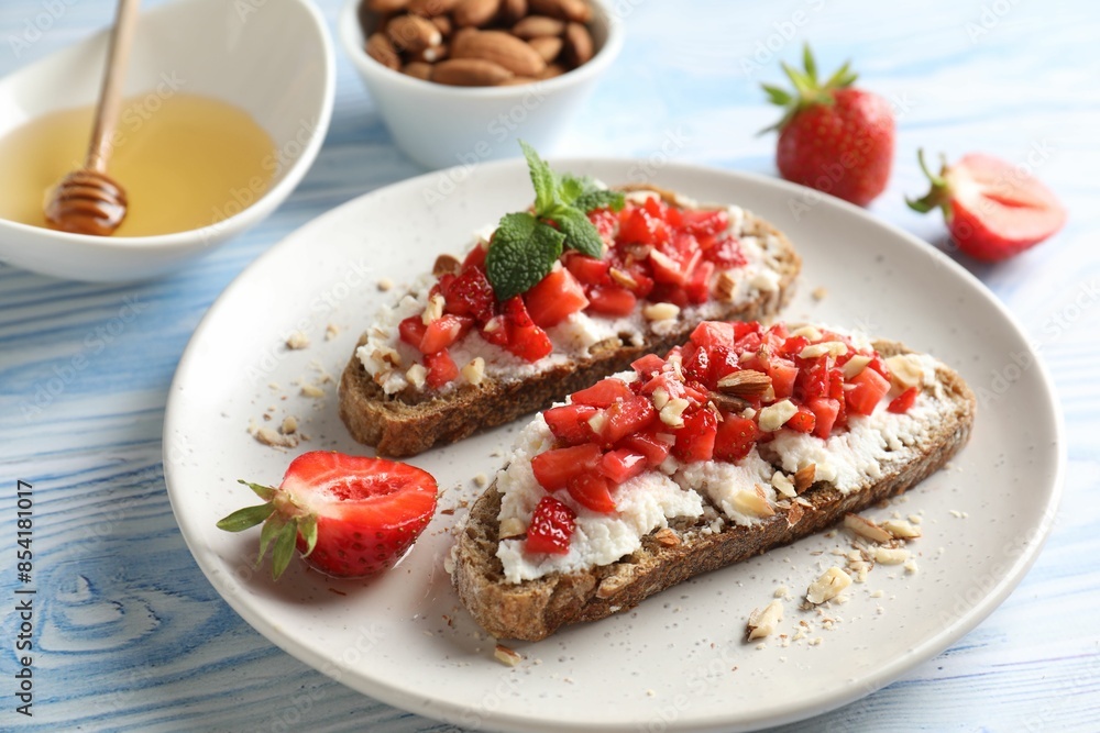Bruschettas with ricotta cheese, chopped strawberries and mint on blue wooden table, closeup Bruschettas with ricotta cheese, chopped strawberries and mint on blue wooden table, closeup