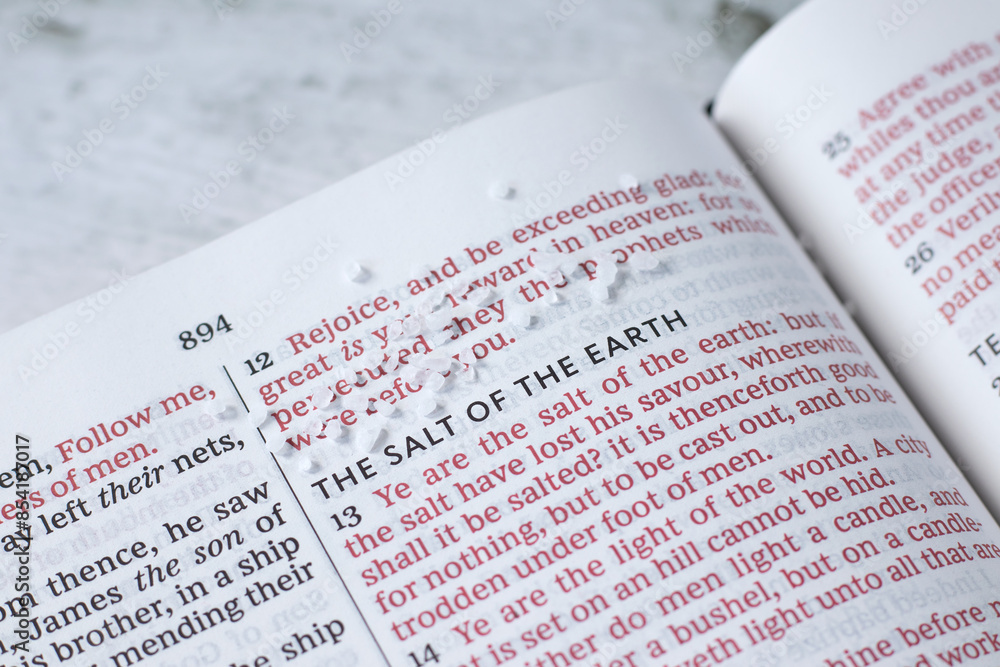 Obraz premium Salt of the earth, biblical verses in open holy book on wooden table. Close-up. Christian concept.