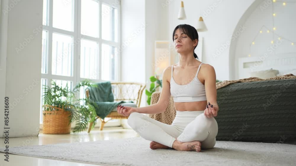 Yoga mindfulness meditation. Young healthy woman practicing yoga in living room at home. Woman sitting in lotus pose meditating smiling relaxing indoor. Girl doing breathing practice. Yoga at home Yoga mindfulness meditation. Young healthy woman practicing yoga in living room at home. Woman sitting in lotus pose meditating smiling relaxing indoor. Girl doing breathing practice. Yoga at home