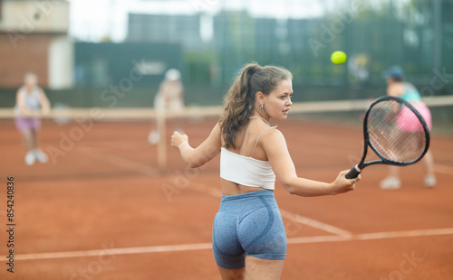 Two young women doubles playing against elderly women in tennis on court