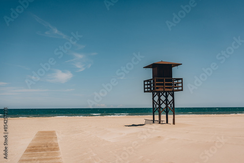 Φωτογραφία A solitary lifeguard tower standing on an empty, sandy beach with the sea and sky in the background