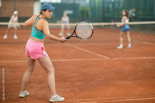 Two young women doubles playing against elderly women in tennis on court © JackF