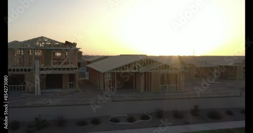 Golden hour sun rays shine through a single family home under construction in a middle class Arizona suburb 03