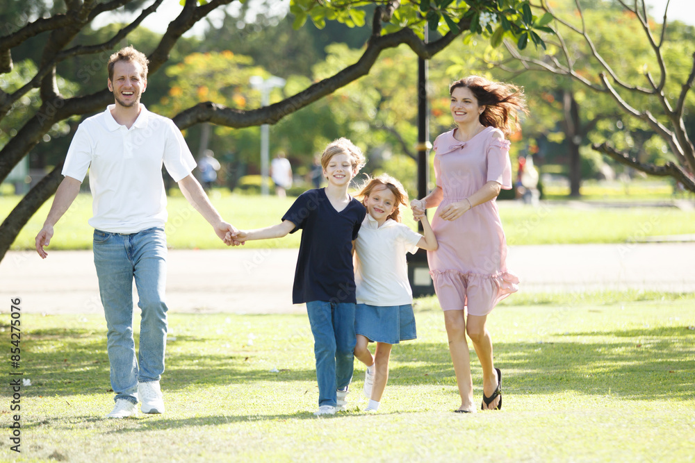 Happy family relaxing together at the park, caucasian family with father, mother, and children walking at the park. Happy family relaxing together at the park, caucasian family with father, mother, and children walking at the park.