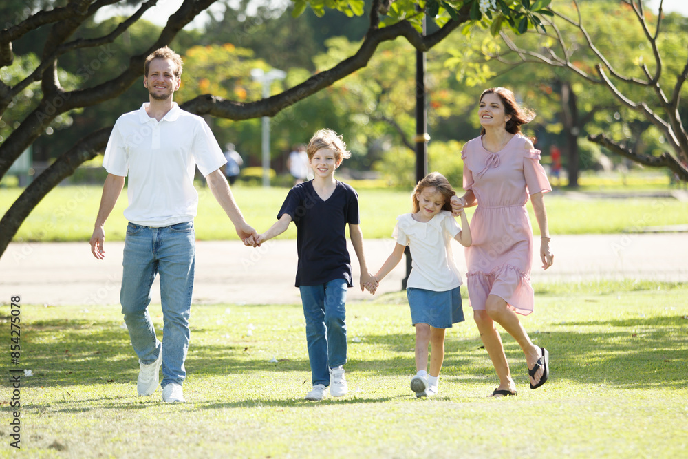 Happy family relaxing together at the park, caucasian family with father, mother, and children walking at the park. Happy family relaxing together at the park, caucasian family with father, mother, and children walking at the park.