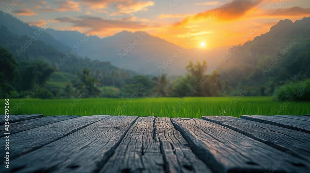 Fototapeta premium A serene sunset illuminating green fields and distant mountains, viewed from a rustic wooden deck, creating a picturesque landscape.