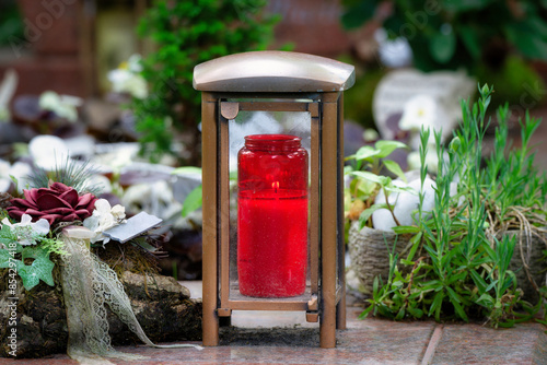 modern metal grave lantern with  burning devotional candle on a grave with tasteful decorations