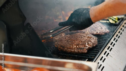 Slow motion of grilling burgers on a BBQ with flames dancing in the background, ideal for a summer weekend celebration