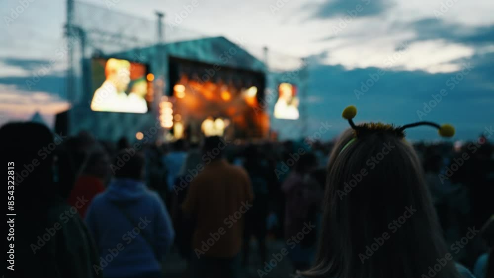 Captured in slow motion, a joyful crowd is savoring an outdoor music festival at dusk under a summer sky Captured in slow motion, a joyful crowd is savoring an outdoor music festival at dusk under a summer sky