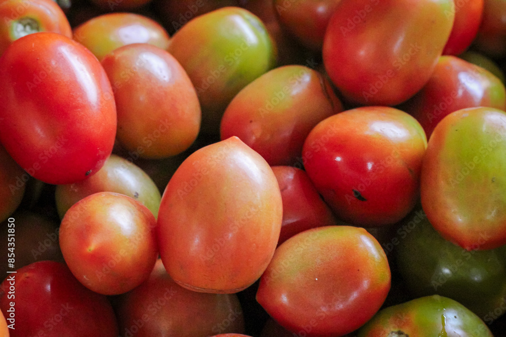 Small fresh red tomatoes, neatly arranged in a wooden crate at a vegetable stall Small fresh red tomatoes, neatly arranged in a wooden crate at a vegetable stall