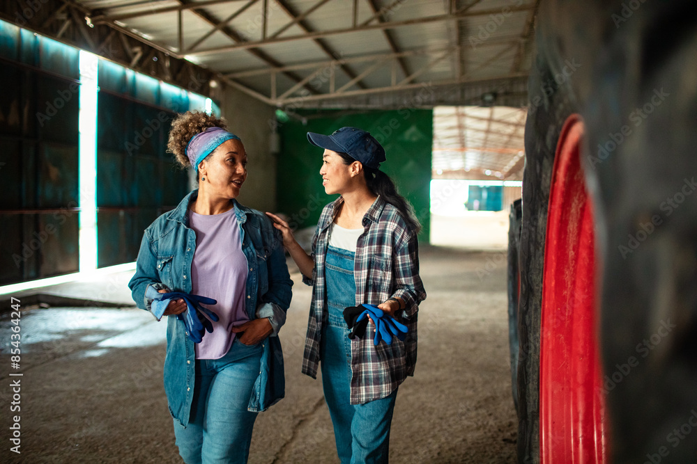 Two female farmers discussing inside tractor shed Two female farmers discussing inside tractor shed