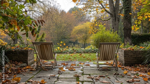 Two vintage deck chairs, stone patio, and autumn foliage in a serene back garden setting photo