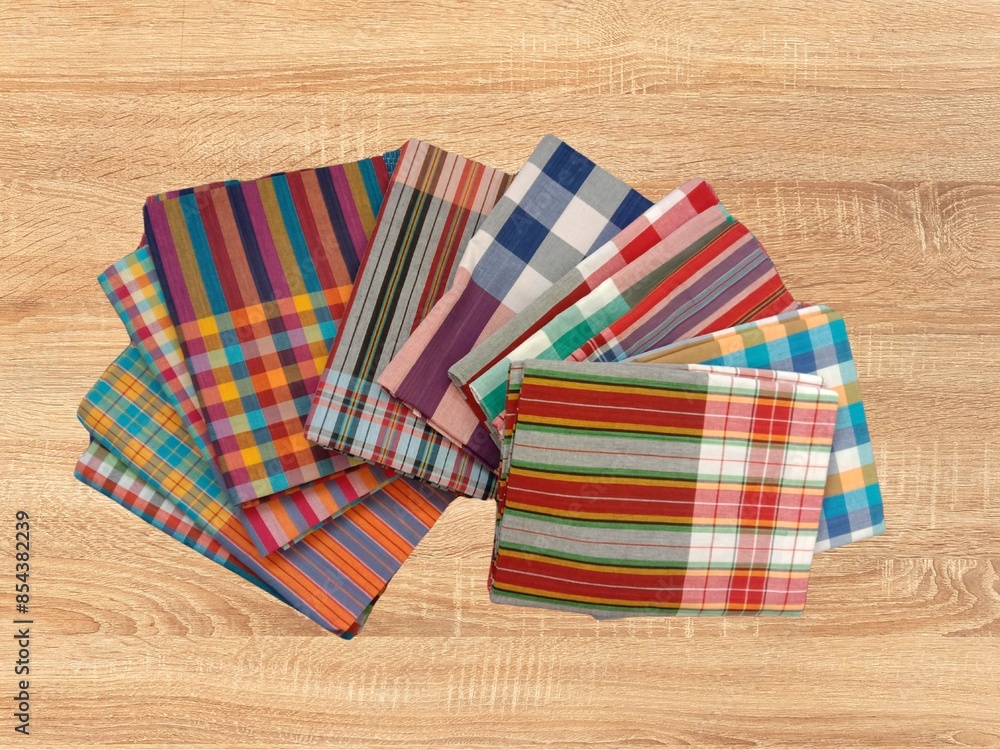 Obraz premium Loincloth multicolor handmade handwoven Thai traditional fabric textile style stacked several pieces on wooden background.