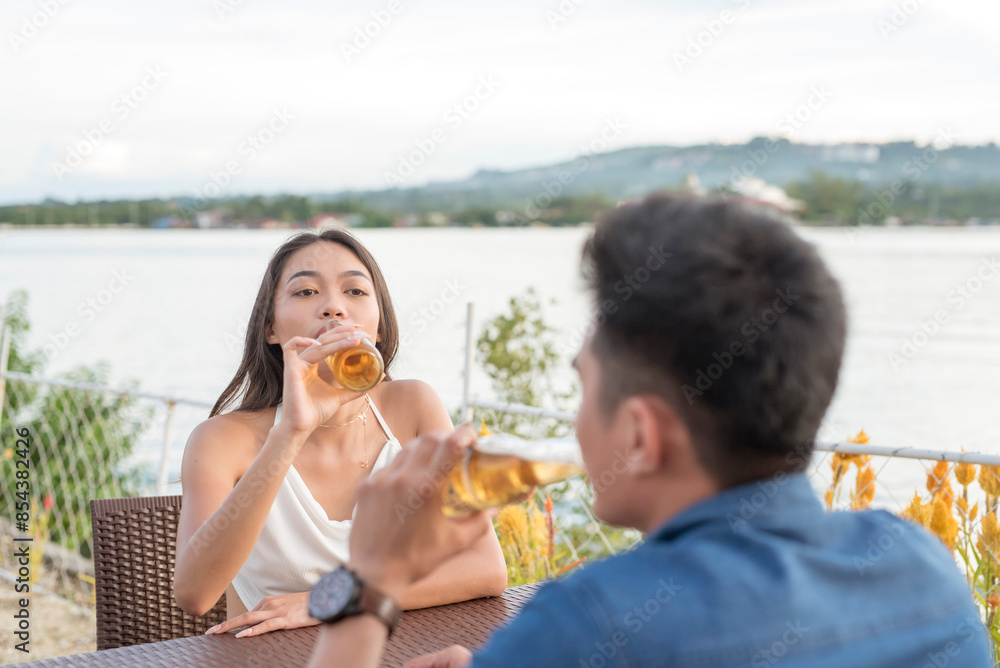 Obraz premium Young couple enjoying drinks by the waterfront