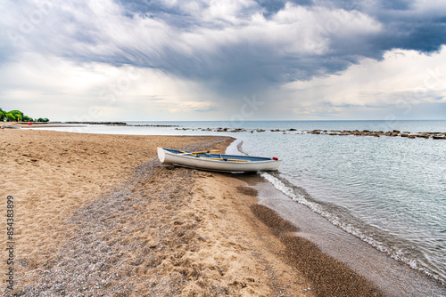 Photography boat on the beach: a white rowing skiff with oars sits at the waters edge on the