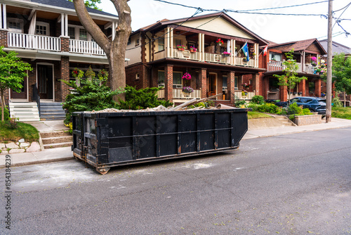 Photography A roll-off construction dumpster filled with broken plaster and lath outside a residential renovation project in an older neighourhood