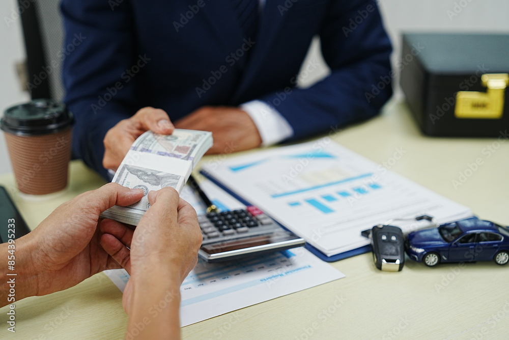 A businessman signs a contract for car insurance in an office. Holding a pen, he finalizes the agreement with the agent. This ensures protection and security for his new vehicle. A businessman signs a contract for car insurance in an office. Holding a pen, he finalizes the agreement with the agent. This ensures protection and security for his new vehicle.
