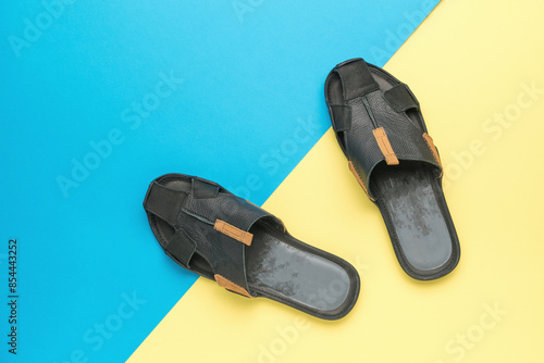 Black Leather Sandals on Vibrant Blue and Yellow Background - Modern Summer Footwear