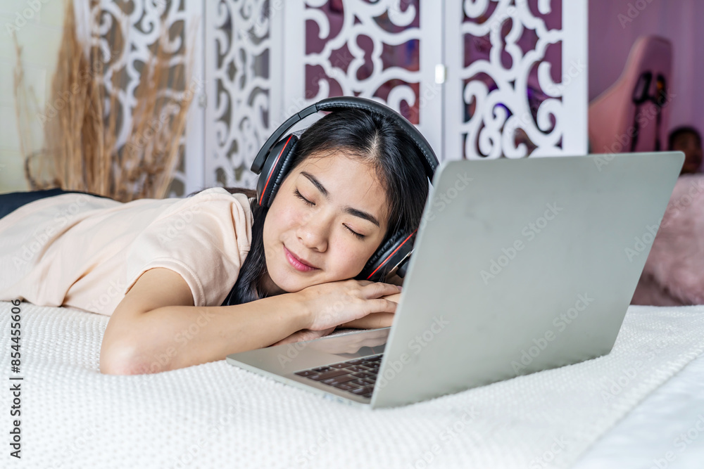 Young asian beautiful internet addict woman in pajamas on bed at home bedroom asleep while working with laptop computer, Resting after the work Young asian beautiful internet addict woman in pajamas on bed at home bedroom asleep while working with laptop computer, Resting after the work