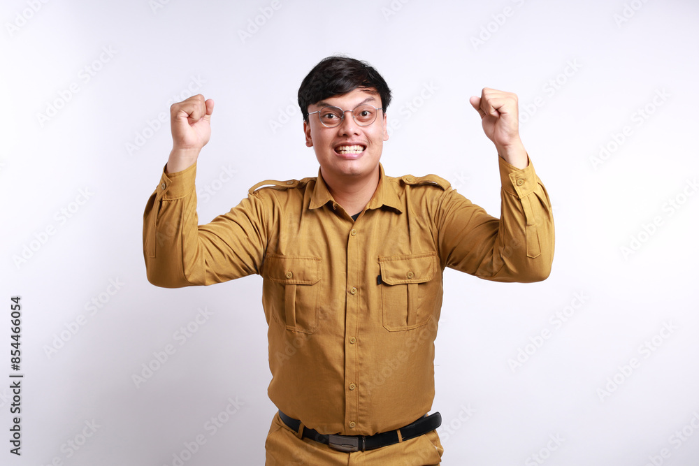Fototapeta premium Excited male worker wearing brown uniform raised his arm. pegawai negeri sipil indonesian government employees
