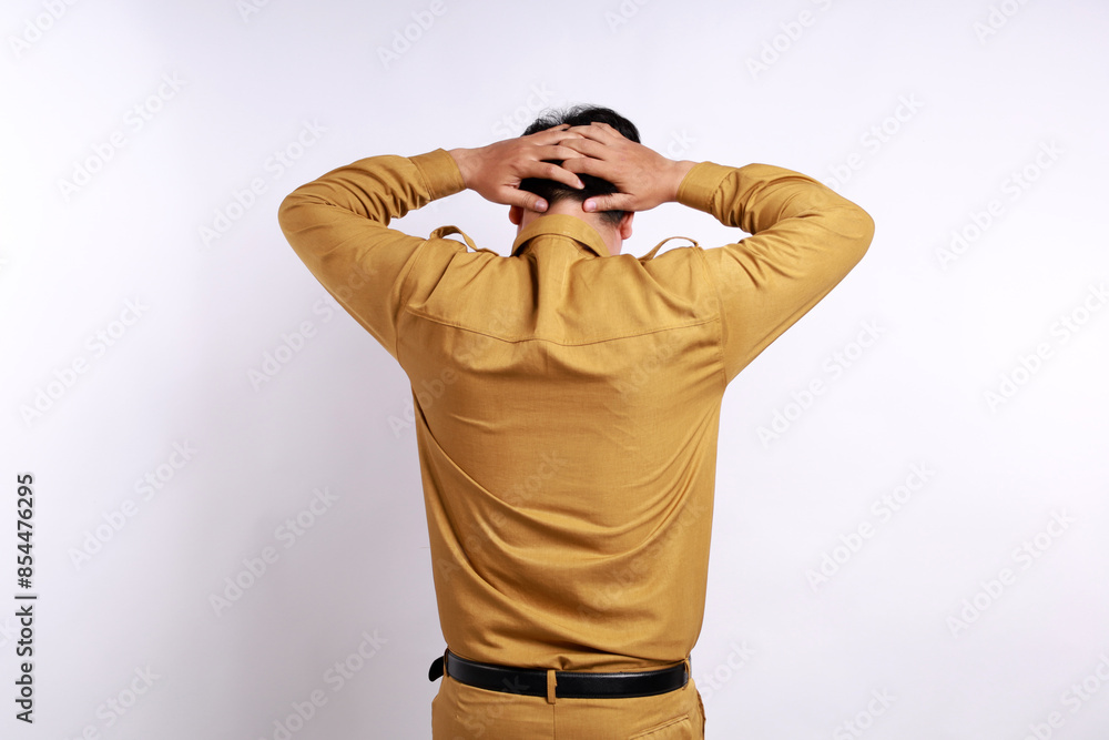 A portrait of an Asian Indonesian government employees, photographed from behind, experiencing a headache and holding his head. Isolated against a white background A portrait of an Asian Indonesian government employees, photographed from behind, experiencing a headache and holding his head. Isolated against a white background