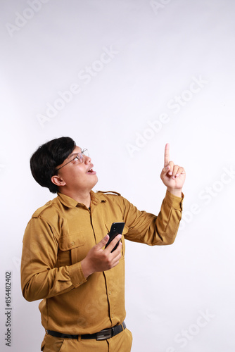 Smiling government worker man holding her smartphone and pointing to copy space above her. PNS wearing khaki uniform.