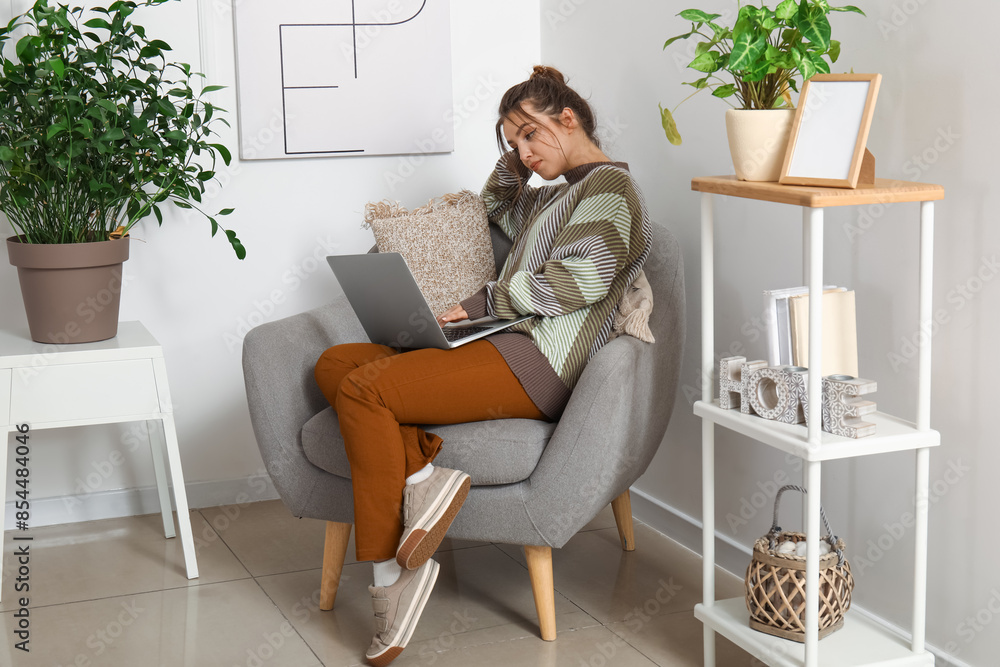 Female freelancer working with laptop in armchair at home Female freelancer working with laptop in armchair at home