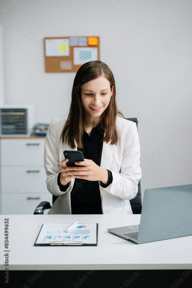 Young woman using laptop and tablet while sitting at her working place. Concentrated at work.. Young woman using laptop and tablet while sitting at her working place. Concentrated at work..