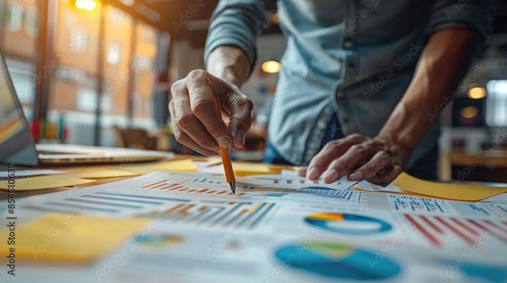 Obraz premium Close-up of a Person Analyzing Charts and Graphs